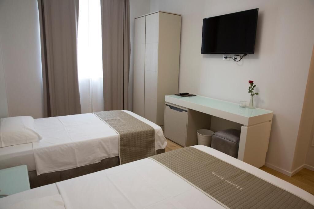 A hotel room with two beds, a desk, a television, and a wardrobe.