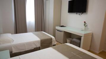 A hotel room with two beds, a desk, a television, and a wardrobe.