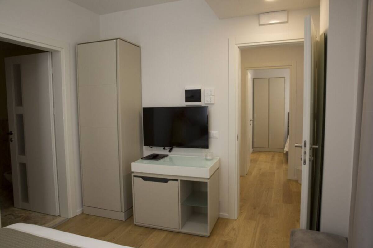 A compact hotel room with a kitchenette, a flat-screen TV, and a small cabinet.