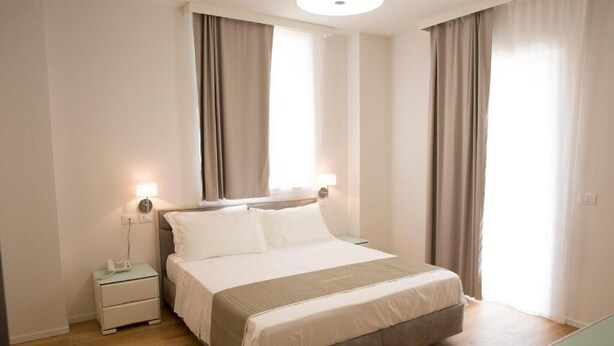Un dormitorio con cama, mesitas de noche y una lámpara.