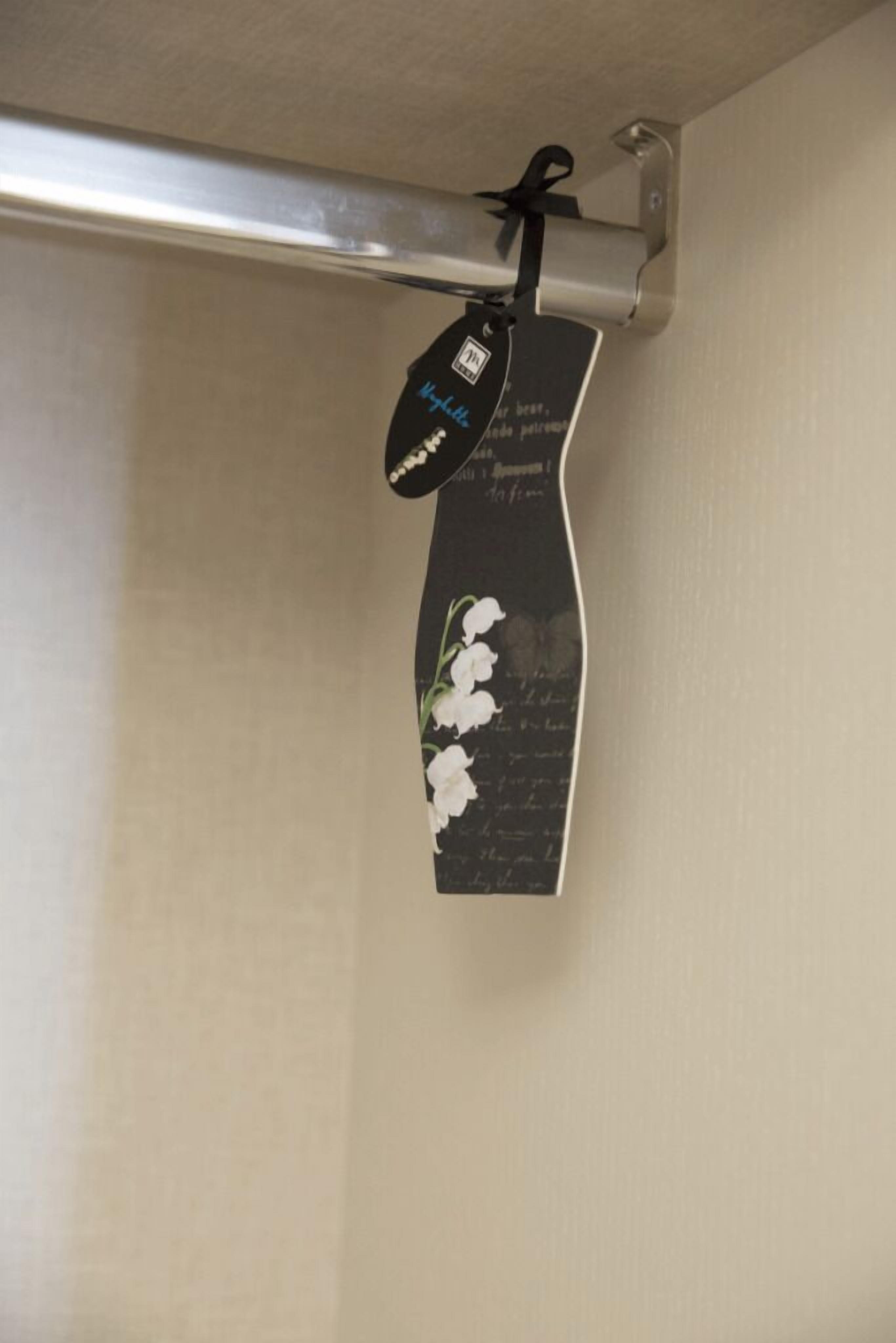 Un letrero fijado a la pared con fondo negro y flores blancas, sujeto a un soporte metálico.