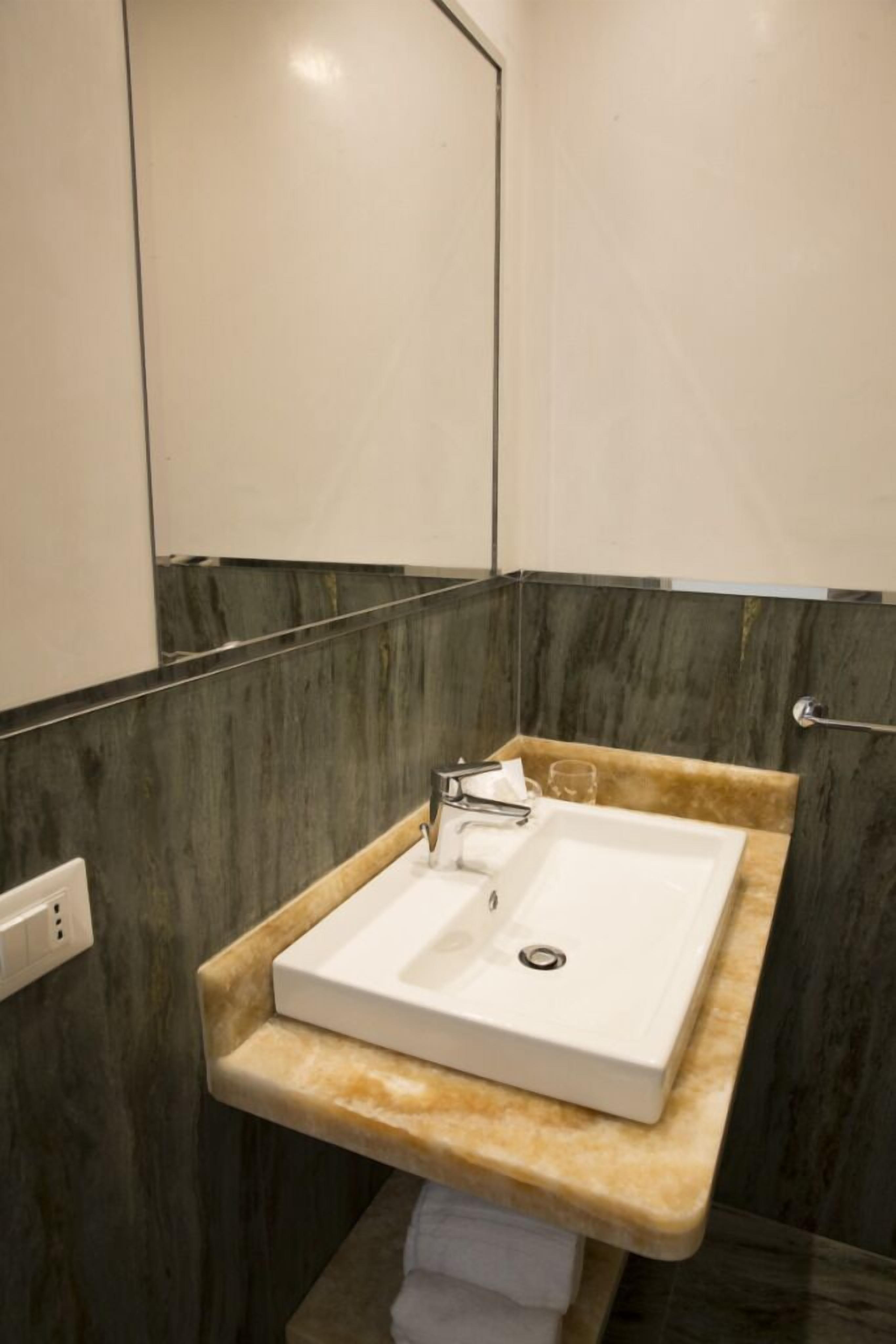 A modern bathroom with a marble vanity, a white sink, and a towel rack.