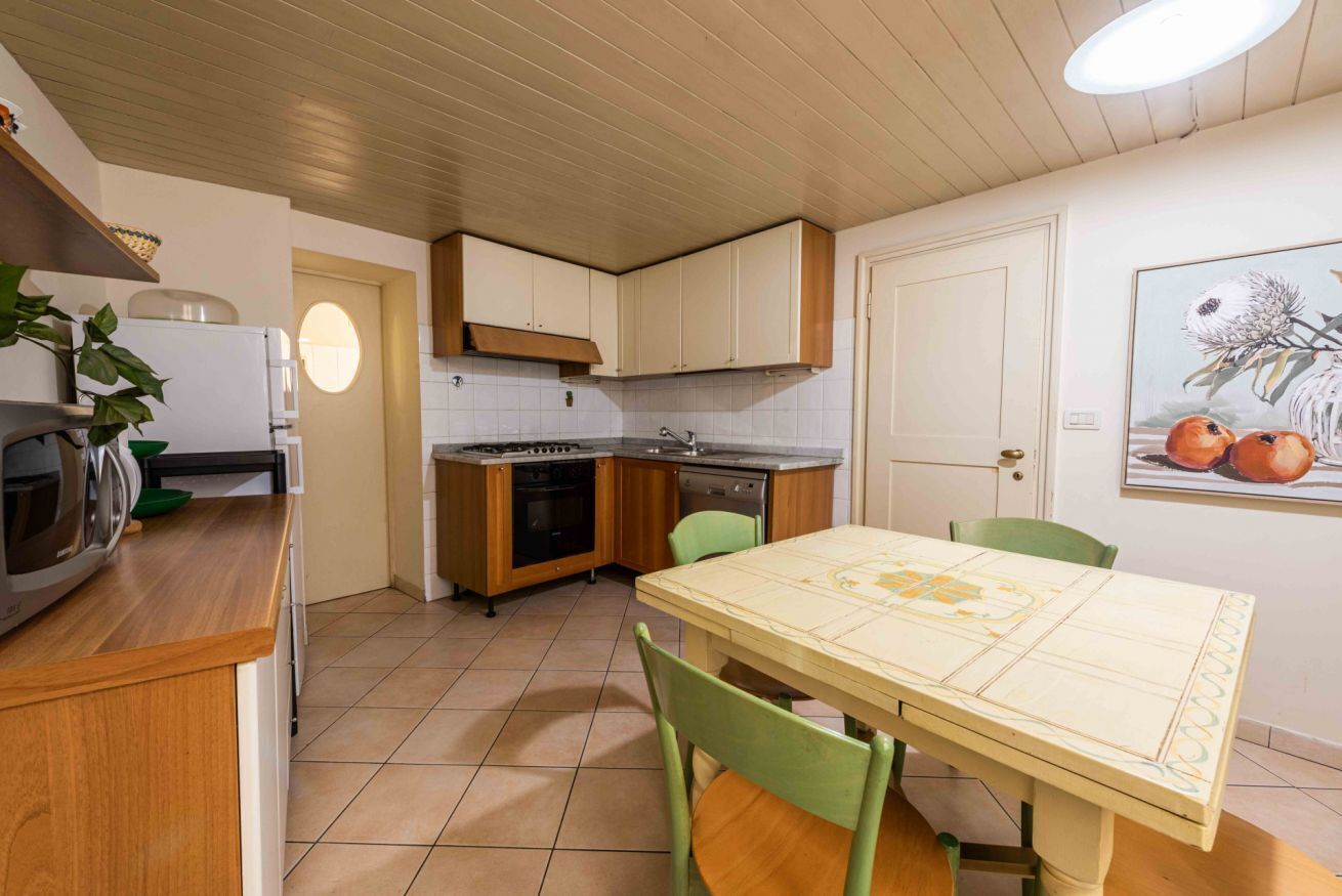 A compact kitchen with a dining table, chairs, a refrigerator, stove, sink, and cabinets.