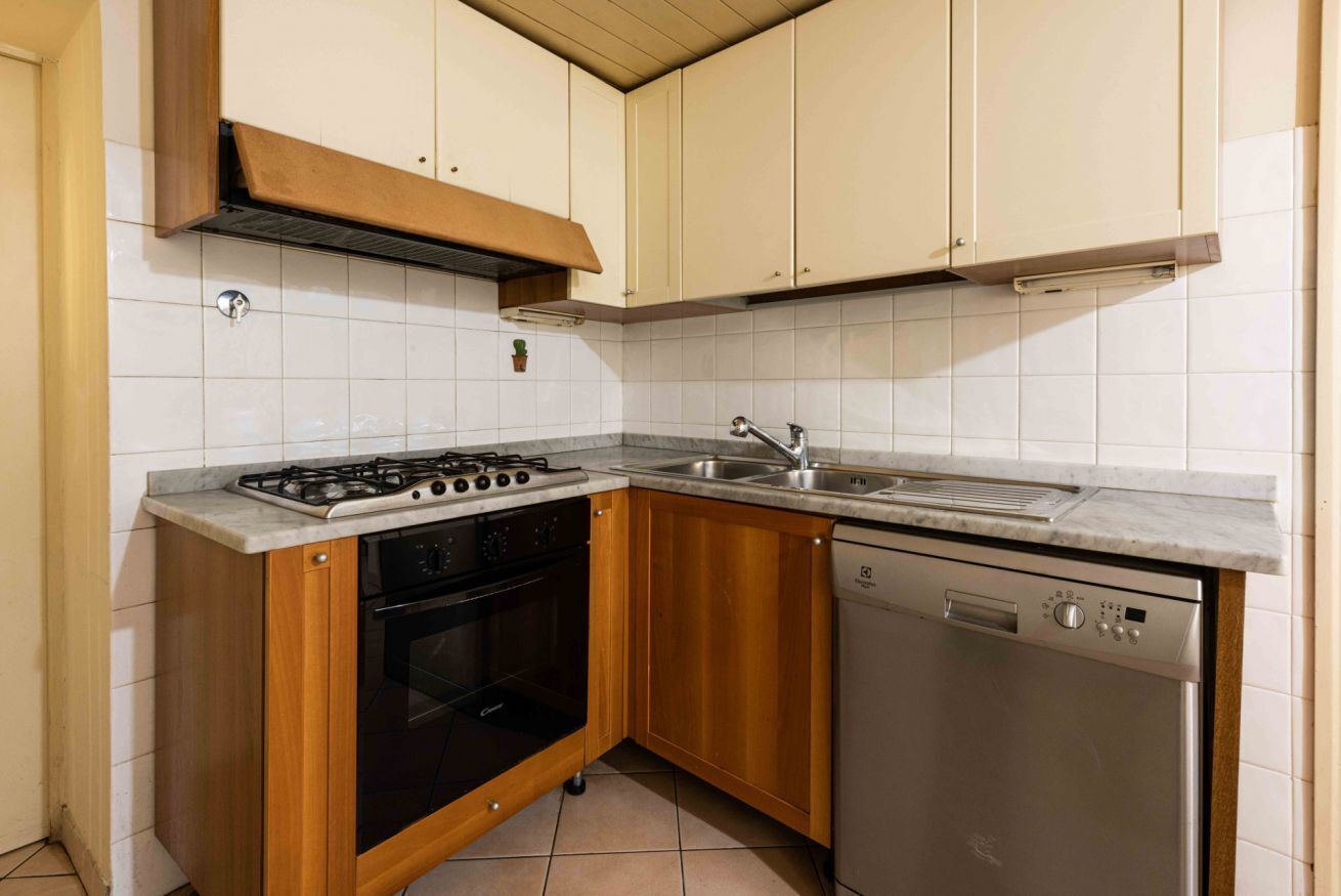 A kitchen with a gas stove, oven, dishwasher, and a sink.