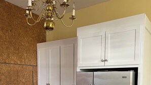 Una cucina con mobili bianchi, un frigorifero in acciaio inossidabile e un lampadario.