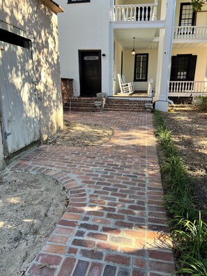 Un sendero de ladrillo que lleva a un edificio blanco con porche y una puerta que indica "Around Entrance".