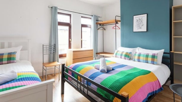 A bedroom with two beds, a desk, and a chair. There is a window with curtains, a wall-mounted shelf, and a framed picture. - Traditional Belfast Home, Walking Distance to City & Titanic Heritage (Belfast)