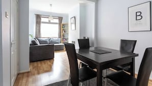 A modern living room with a dark wooden dining table, black chairs, and a grey sofa. - Traditional Belfast Home, Walking Distance to City & Titanic Heritage (Belfast)