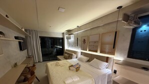Una habitación de hotel moderna con una cama grande, un escritorio y una puerta corredera que da a un balcón.
