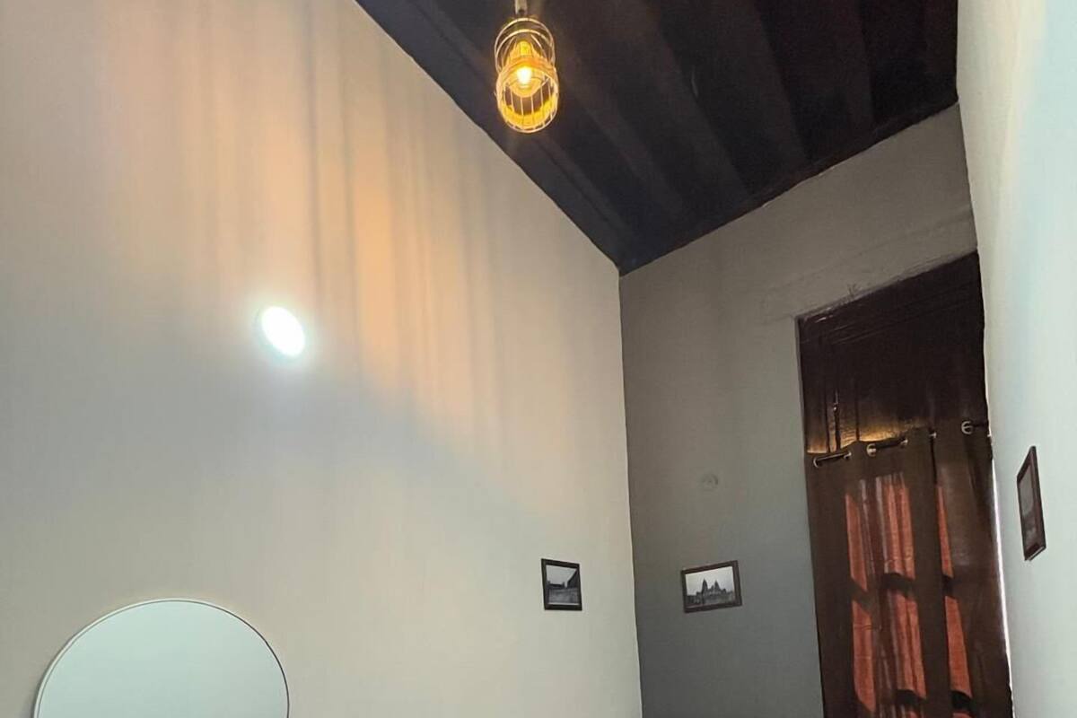 Une chambre à coucher avec un lit, un miroir rond, une petite étagère et un luminaire suspendu.