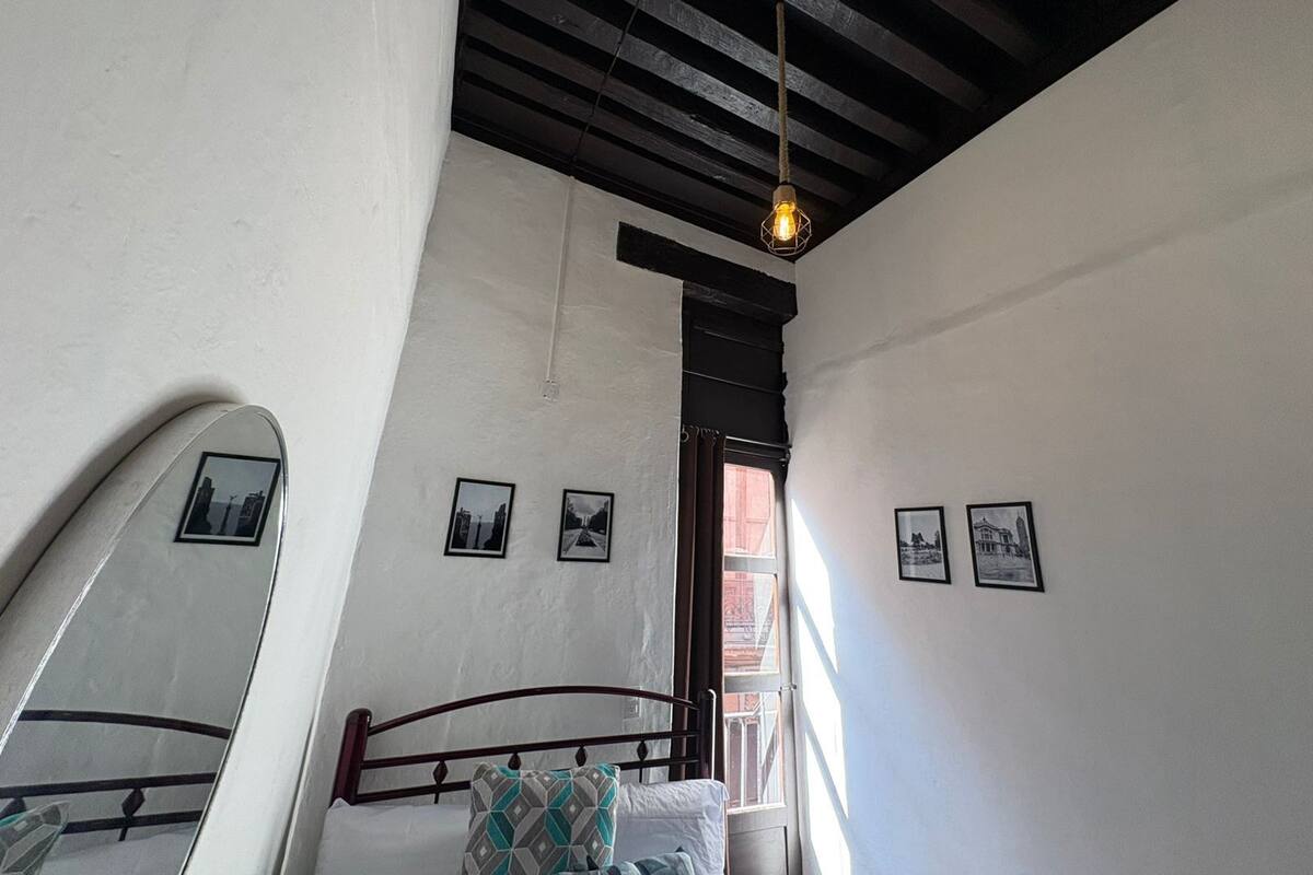 Une chambre à coucher avec un lit, un luminaire suspendu et des tableaux encadrés accrochés au mur.