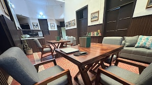 Een moderne woonkamer met een houten salontafel, grijze banken en houten stoelen.