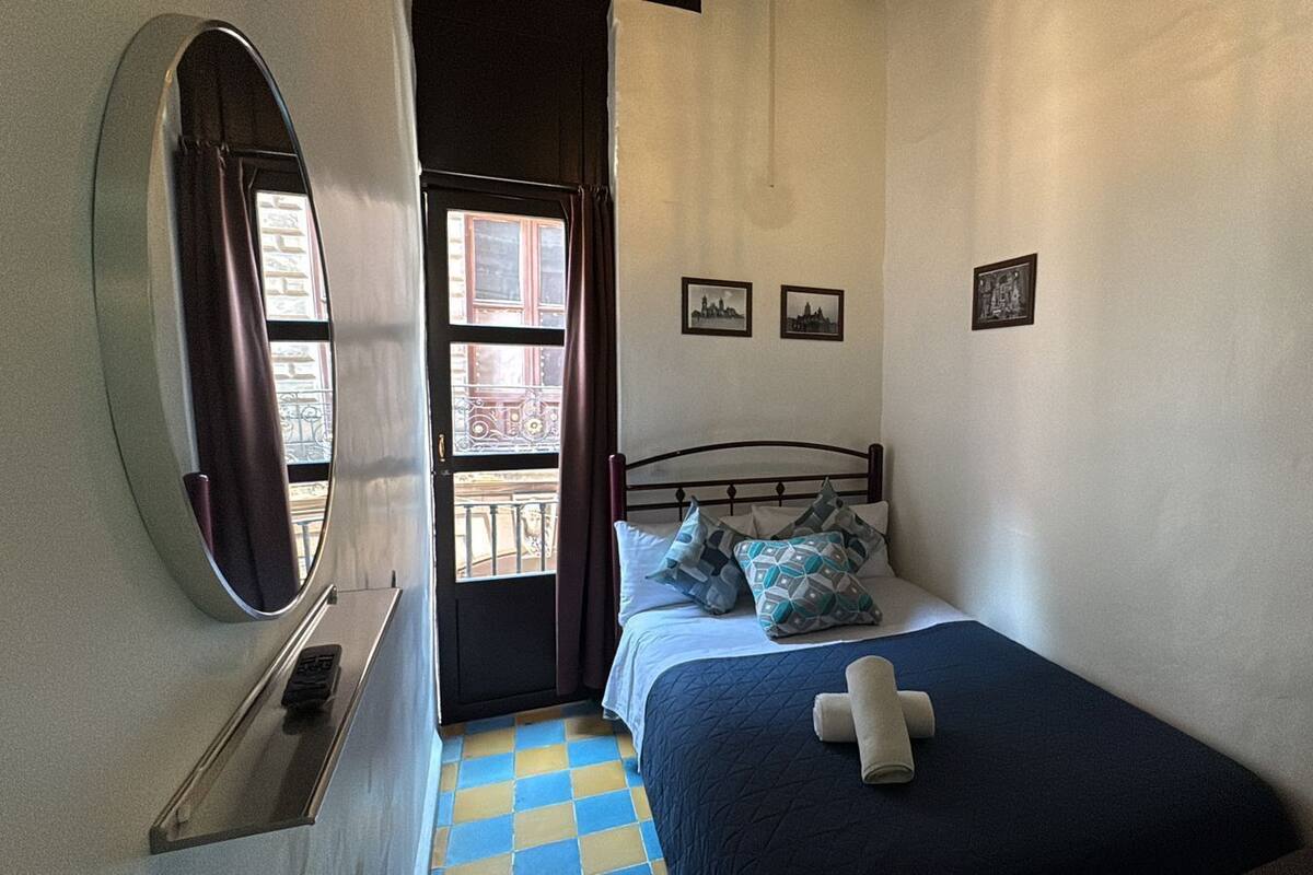 Une chambre à coucher avec un lit, une fenêtre, une porte et un miroir.