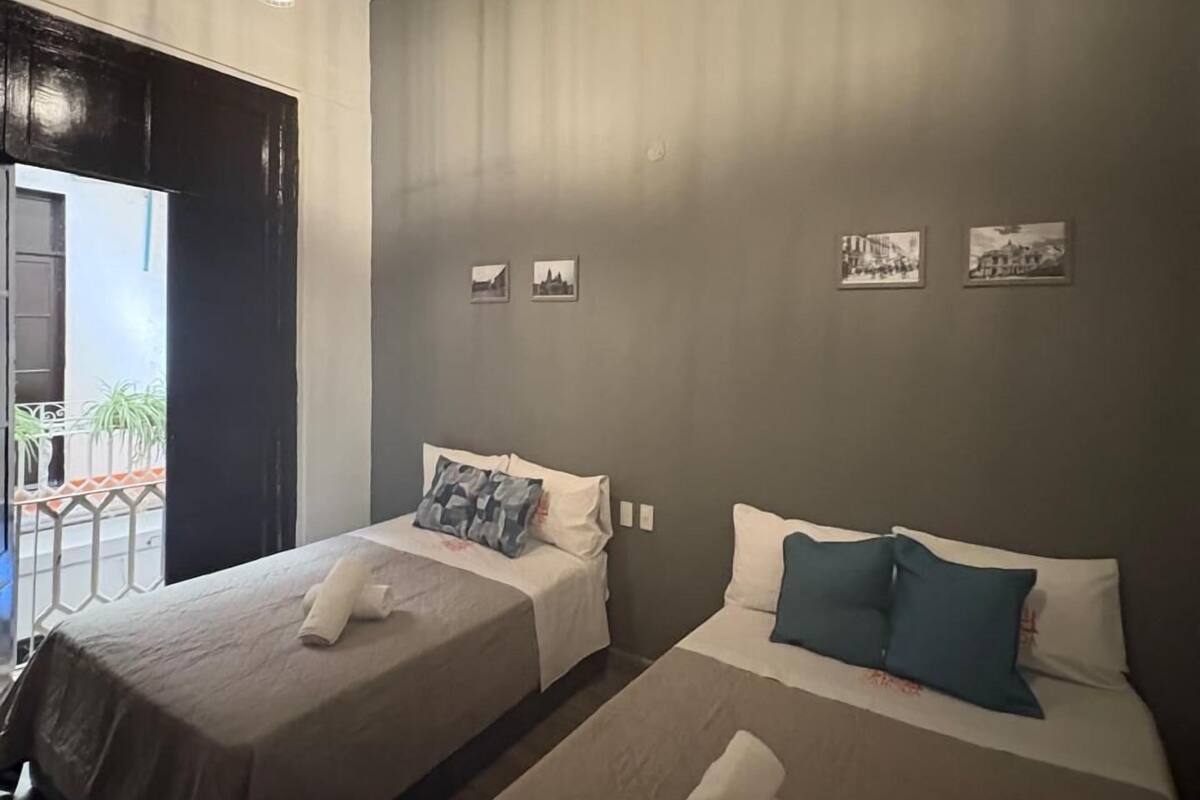 Une chambre d’hôtel avec deux lits, un balcon et vue sur la rue.