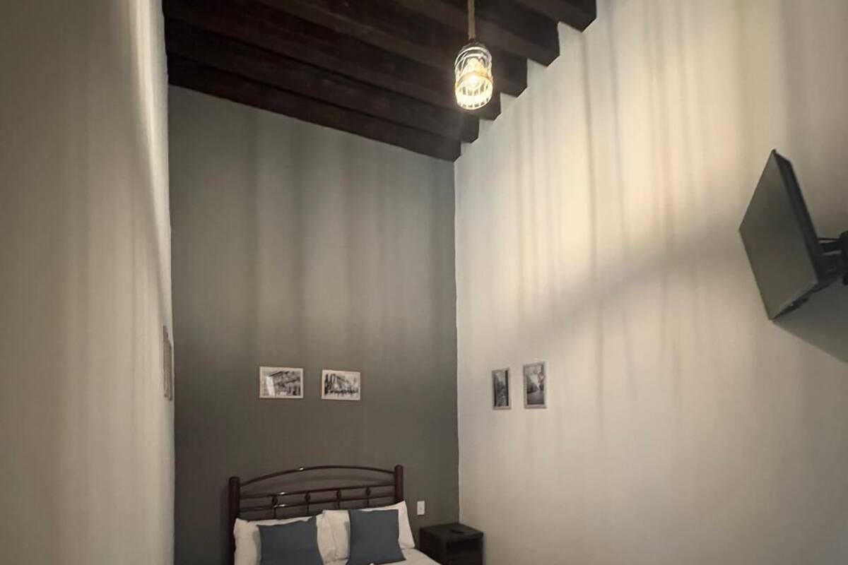 Une chambre à coucher avec un lit, une table de chevet, une lampe fixée au mur et des tableaux encadrés accrochés au mur.