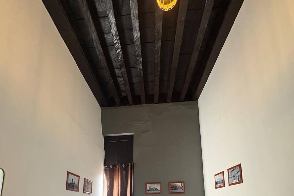 Une petite pièce comprenant un lit, une porte et un luminaire.
