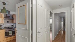 A modern kitchen with wooden cabinets, a gas stove, and a hanging light fixture. - Stylish 1-Bed Flat in London’s Prime Diamond District (London)