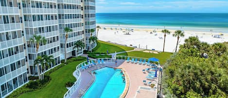 A hotel with a pool, beach view, and a high-rise building.