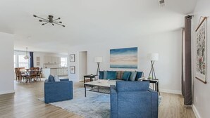 Un salon spacieux avec un canapé bleu, une table basse et un tableau accroché au mur.