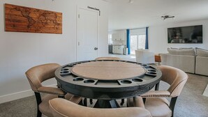 Un coin repas avec une table ronde et quatre chaises, une carte du monde accrochée au mur et une cuisine en arrière-plan.