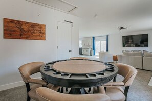 Ein Essbereich mit einem runden Tisch, vier Stühlen, einer Weltkarte an der Wand und einer Küche im Hintergrund.