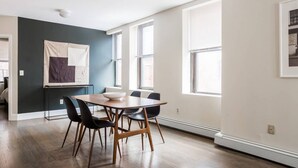 A modern dining area with a wooden table and chairs, a whiteboard on the wall, and large windows providing natural light. - Downtown Boston - close to everything - Laundry in Building, Keyless Entry. Free Air Mattress too. (Boston)