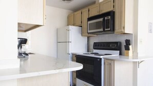 A kitchen with a white refrigerator, a microwave, a stove, and wooden cabinets. - Downtown Boston - close to everything - Laundry in Building, Keyless Entry. Free Air Mattress too. (Boston)