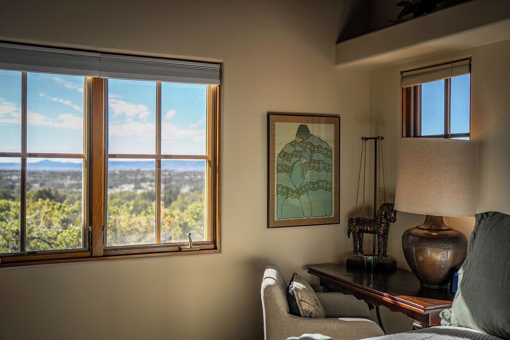 Una habitación con un ventanal amplio que ofrece vistas a un paisaje, una obra de arte enmarcada en la pared, una lámpara y un sofá.