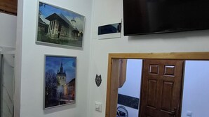 Ein Zimmer mit einem weißen Schrank, einem flachbildfernseher darüber und zwei gerahmten Bildern an der Wand.