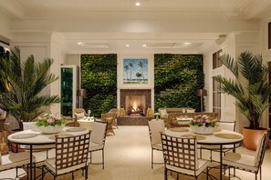 A spacious living area with a fireplace, comfortable seating, and a large green wall. - Olde Naples Hotel (Naples)