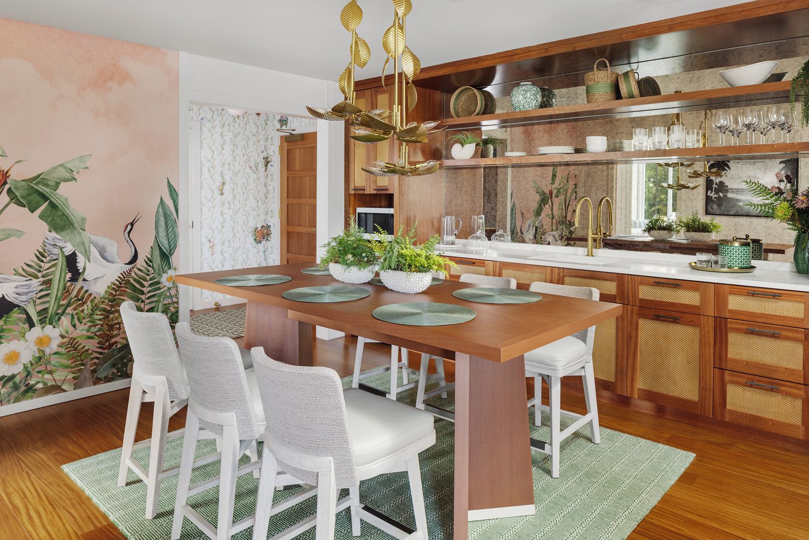 Une cuisine moderne avec une table à manger en bois, des chaises blanches et un îlot central agrémenté de plantes.