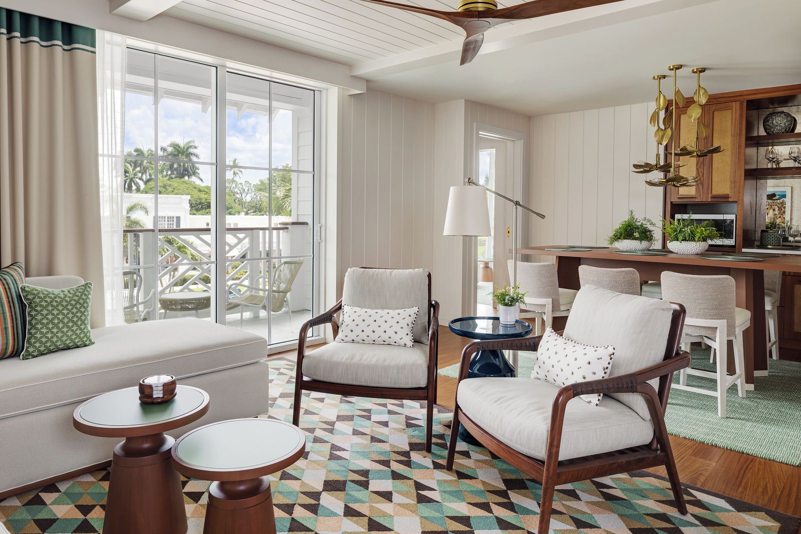 A well-lit living room with a large window, a ceiling fan, and a dining area with wooden furniture.