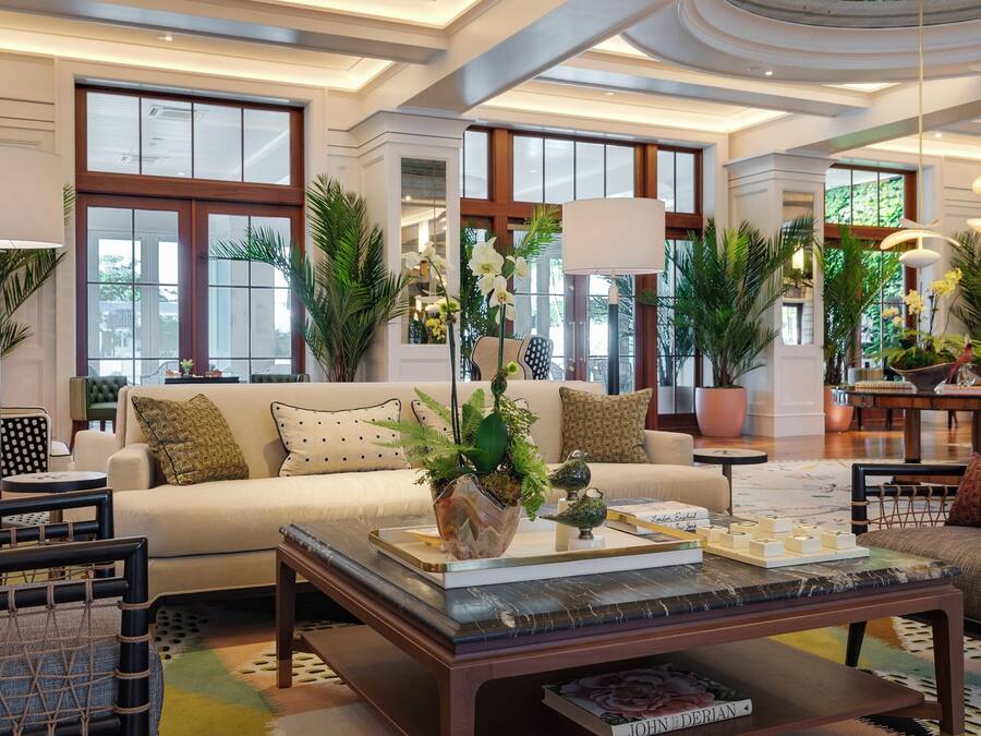 A spacious living area with a sofa, coffee table, and potted plants.