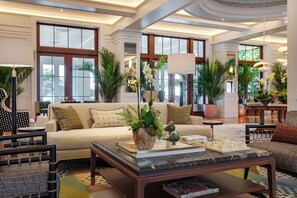 A spacious living area with a sofa, coffee table, and potted plants. - Olde Naples Hotel (Naples)