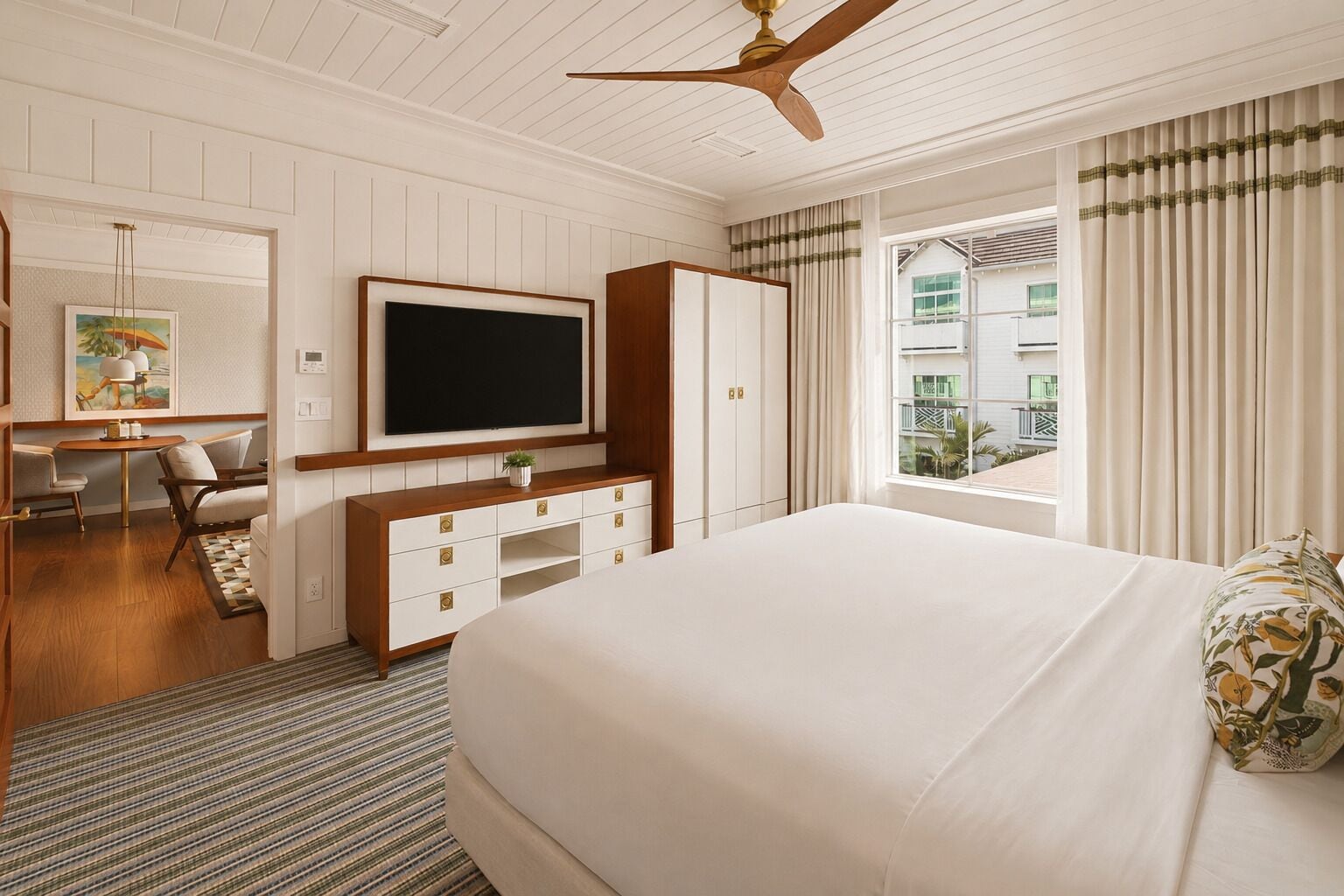 Une chambre d’hôtel avec un grand lit, un téléviseur à écran plat, un bureau avec une chaise et une fenêtre avec des rideaux.