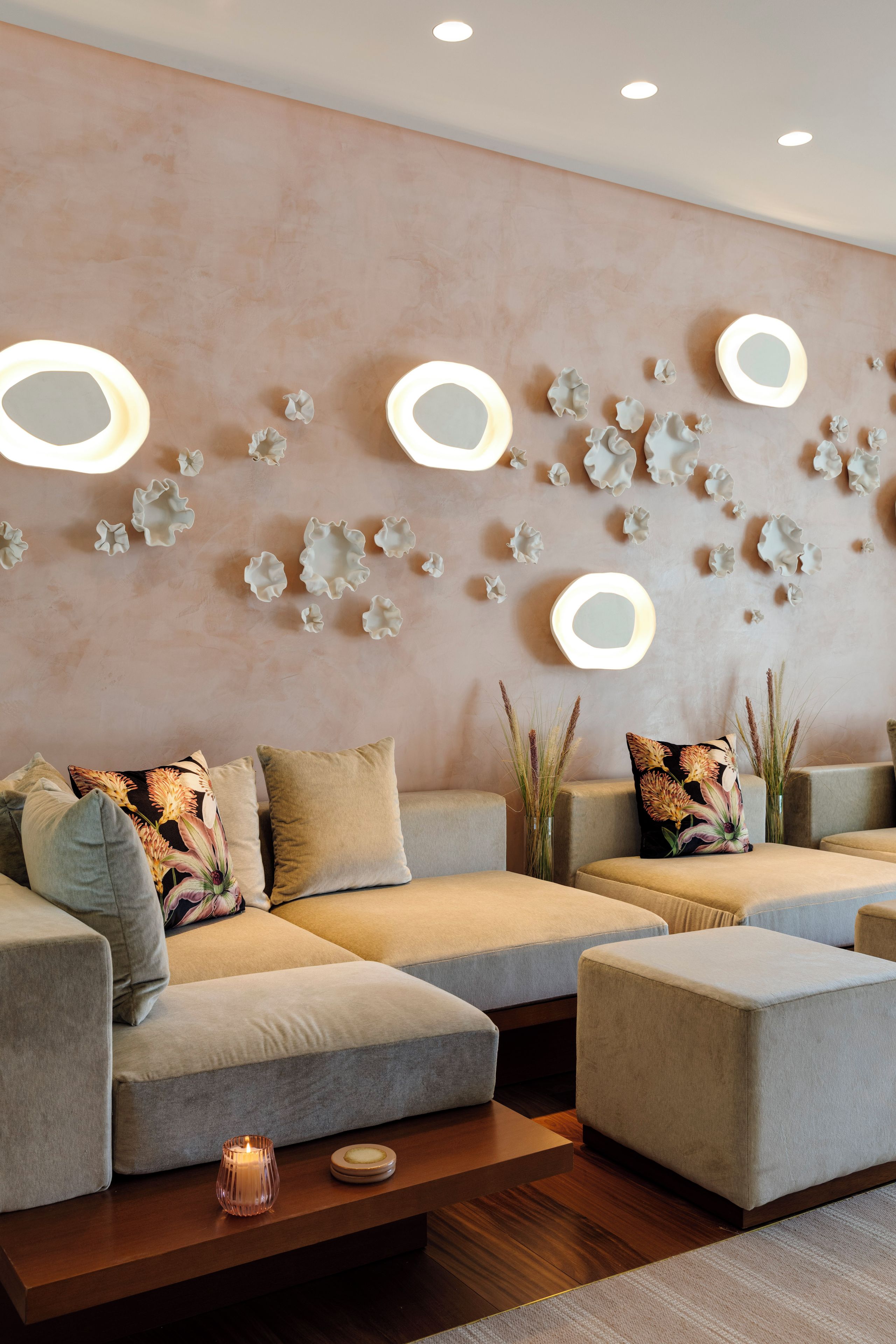 A modern living room with a sectional sofa, a coffee table, and decorative wall lights.