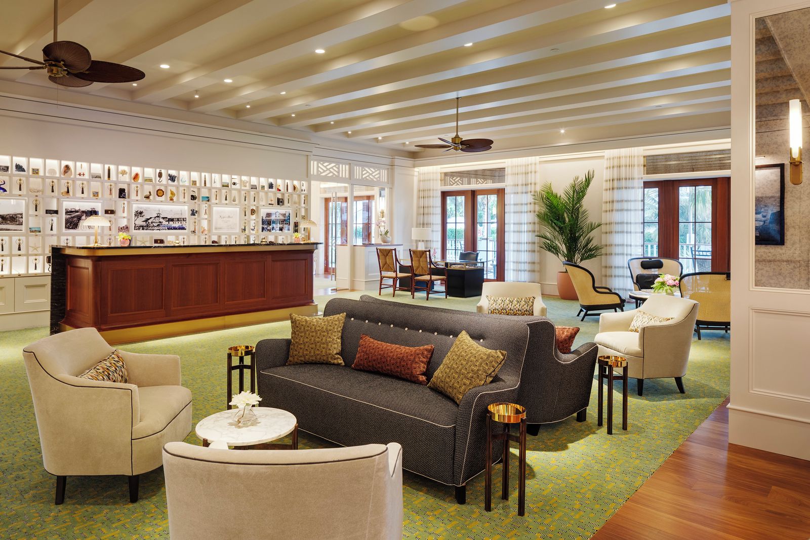 Een hotel lobby met een receptiebalie, een zithoek en een wand met ingekaderde objecten.