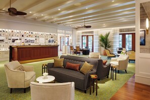 Un hall d’hôtel comprenant un comptoir d’accueil, un espace salon et un mur orné de divers objets encadrés.