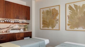A hotel room with a wooden cabinet, a marble countertop, a sink, and two beds with light blue bedding.