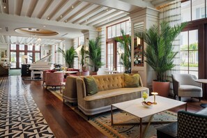 A spacious hotel lobby with a grand piano, comfortable seating, and large windows. - Olde Naples Hotel (Naples)