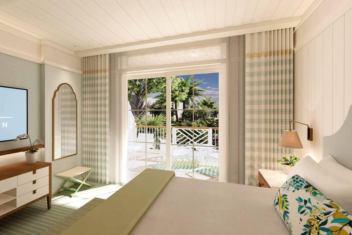 A hotel room with a bed, a TV, a desk, a chair, a mirror, and a view of the outdoor area.