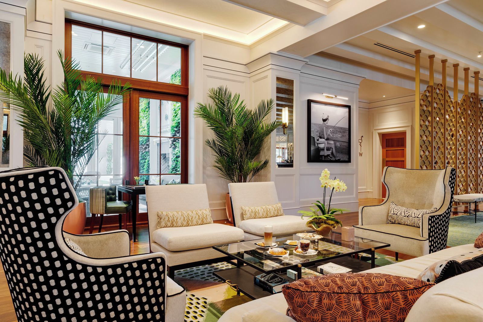A spacious living room with a large window, two sofas, a coffee table, and decorative plants.