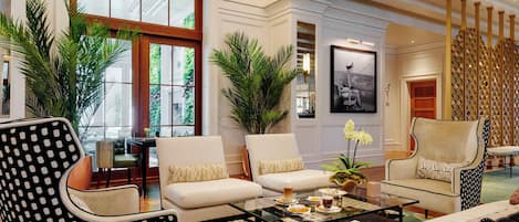 A spacious living room with a large window, two sofas, a coffee table, and decorative plants.