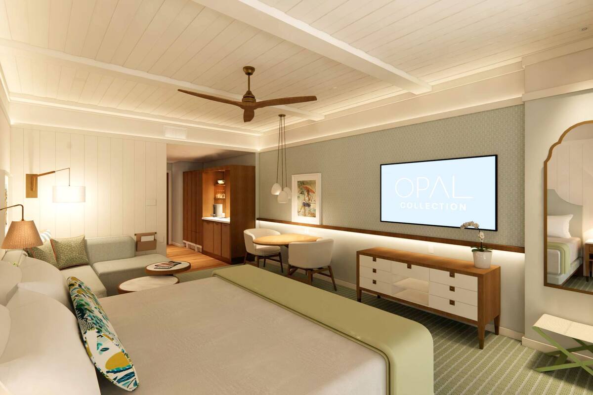 A modern hotel room with a bed, desk, chair, and a TV displaying 'OPAL COLLECTION'.