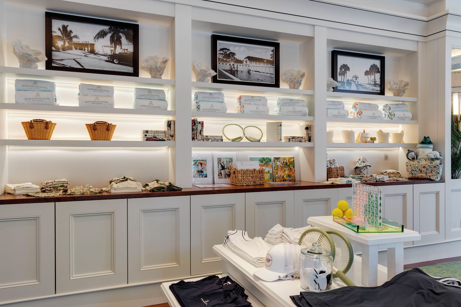A hotel reception area with a counter displaying various amenities and a wall with framed photographs.