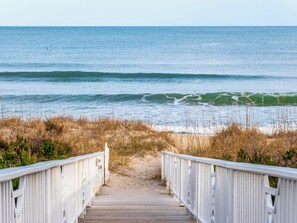 En träpromenad som leder till en strand med vågor.