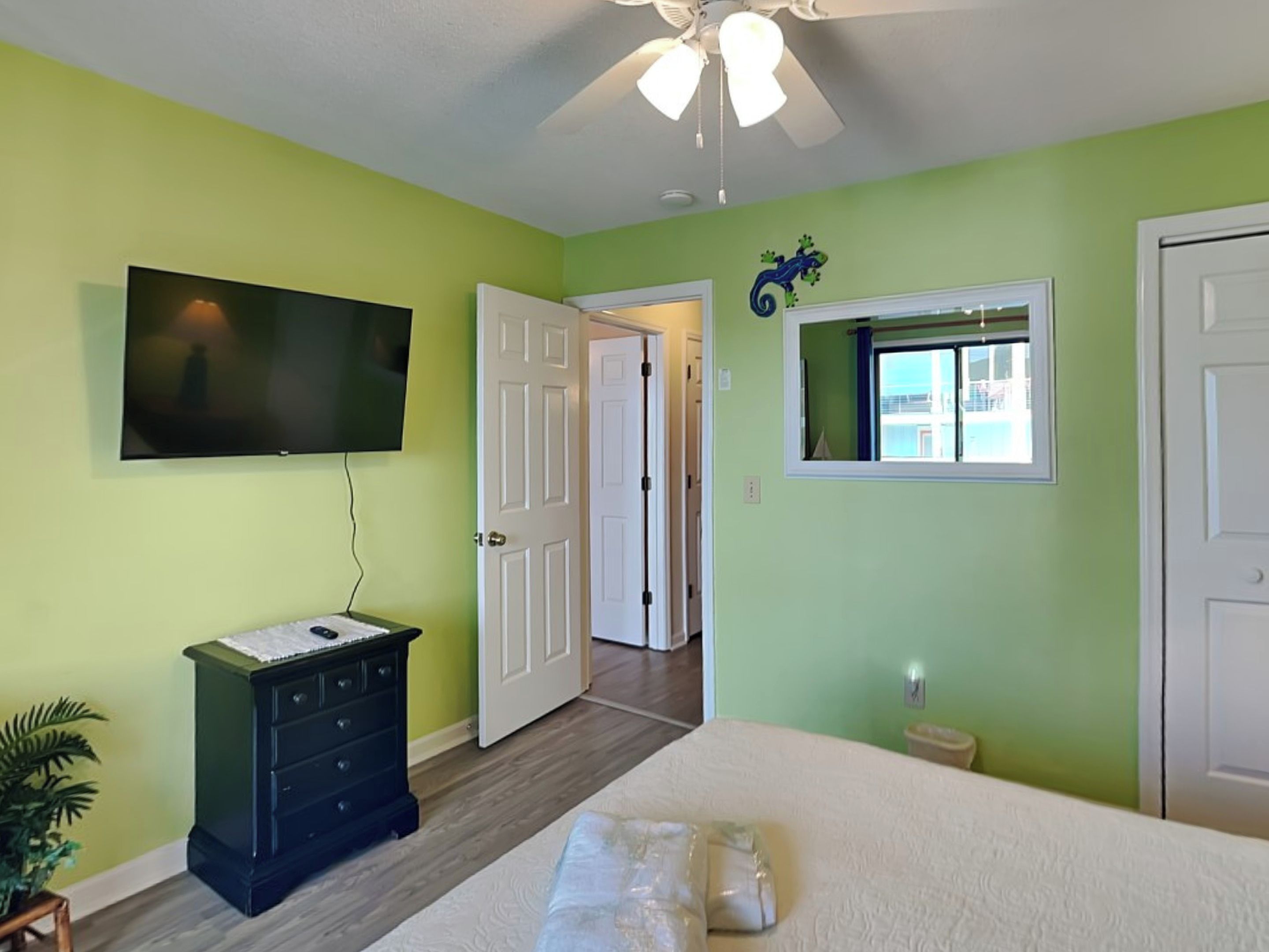 A bedroom with a bed, a dresser, a television, and a ceiling fan.
