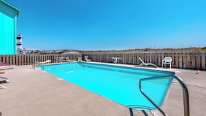 A swimming pool with lounge chairs and a wooden fence. - Winds V1 #3B - My Top Paradise (Carolina Beach)