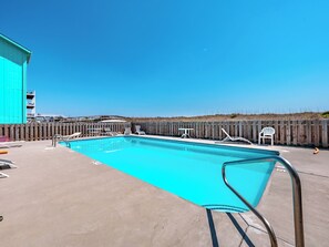 A swimming pool with lounge chairs and a wooden fence. - Winds V1 #3B - My Top Paradise (Carolina Beach)