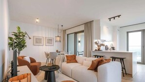 Ein modernes Wohnzimmer mit einer Couch, Sesseln, einem Couchtisch und einem Essbereich.